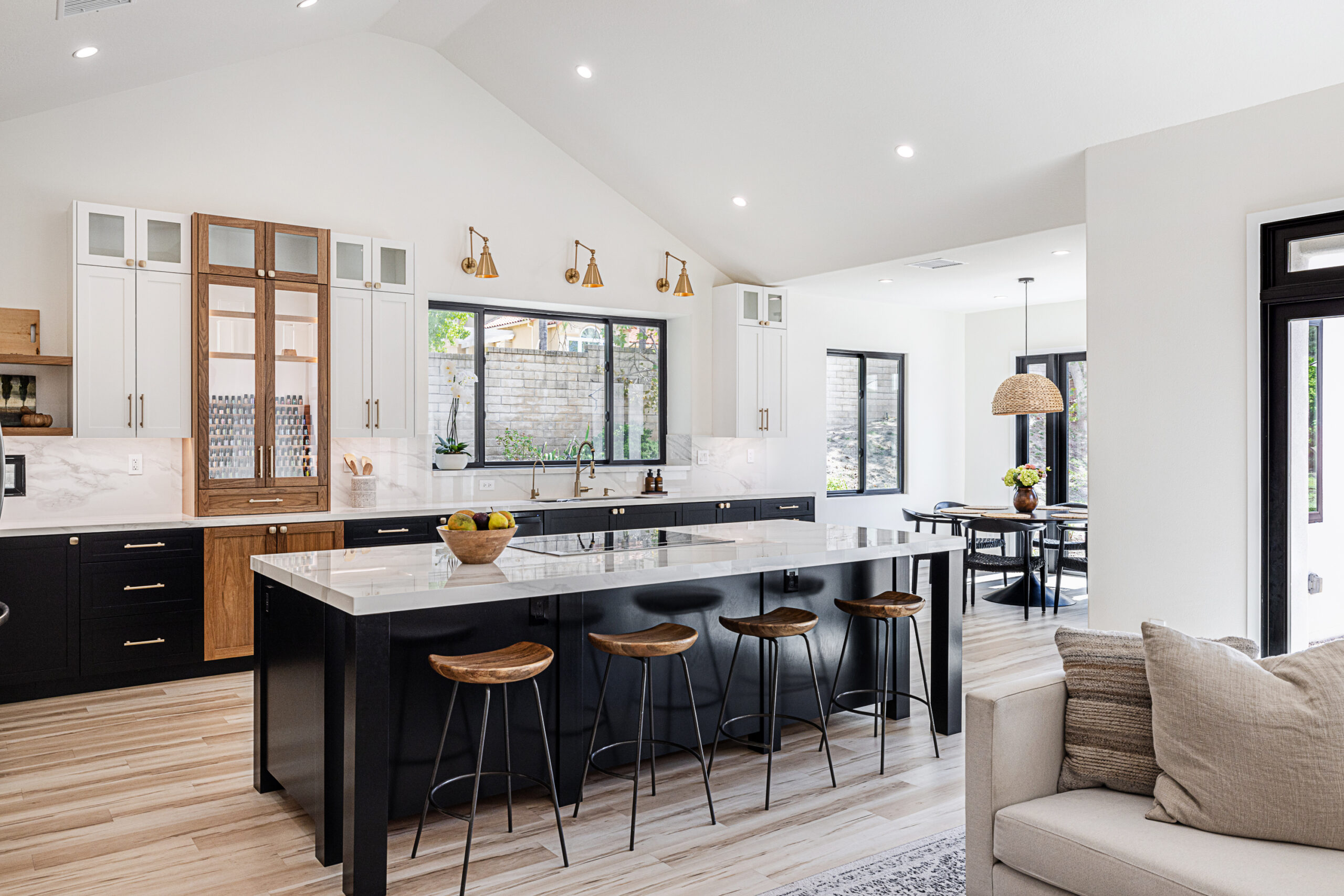 Modern kitchen with black island, white cabinets, and brass pendant lights